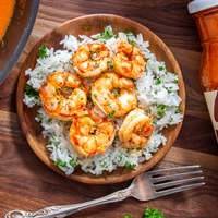recipe: Honey Aleppo Shrimp - Pan of shrimp simmered in Trader Joe's Honey Aleppo Sauce, next to a plate of rice topped with shrimp